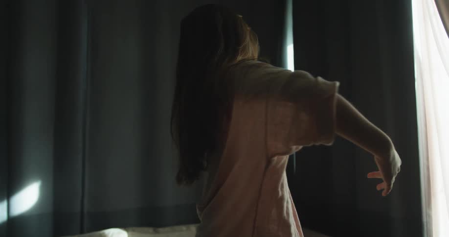 A young woman dances with her arms out in her living room