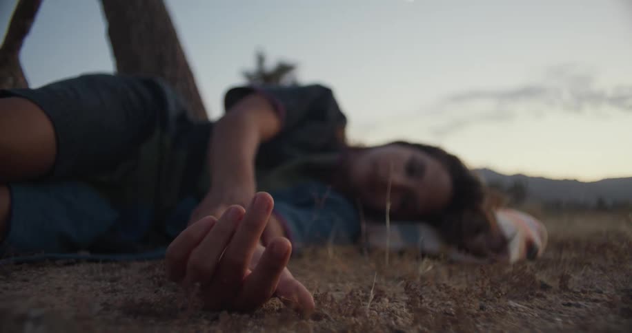 Latin woman lying on her side and moving her fingers one by one at an outdoors field