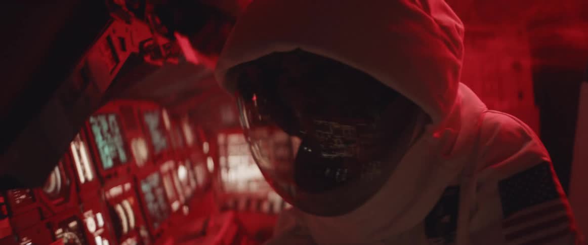 An astronaut concentrates while standing at the instrument panel as their surroundings are shaking violently