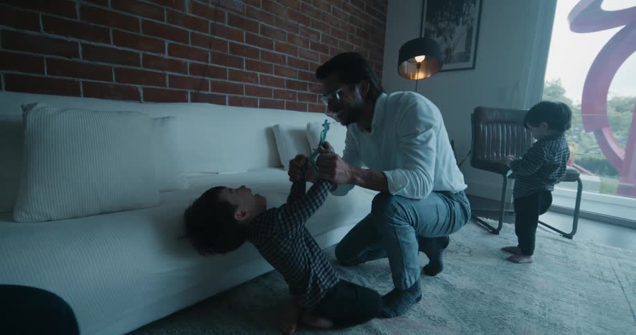 Father playing and having fun with his young boys in the living room