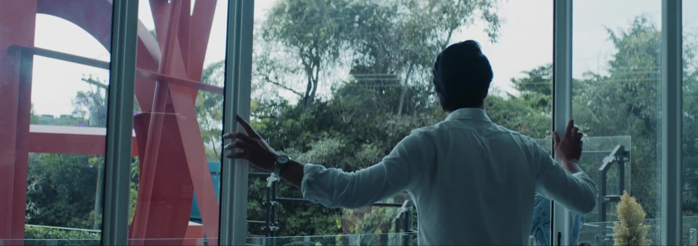 Man opening up the sliding glass door while a woman is standing in the balcony ahead