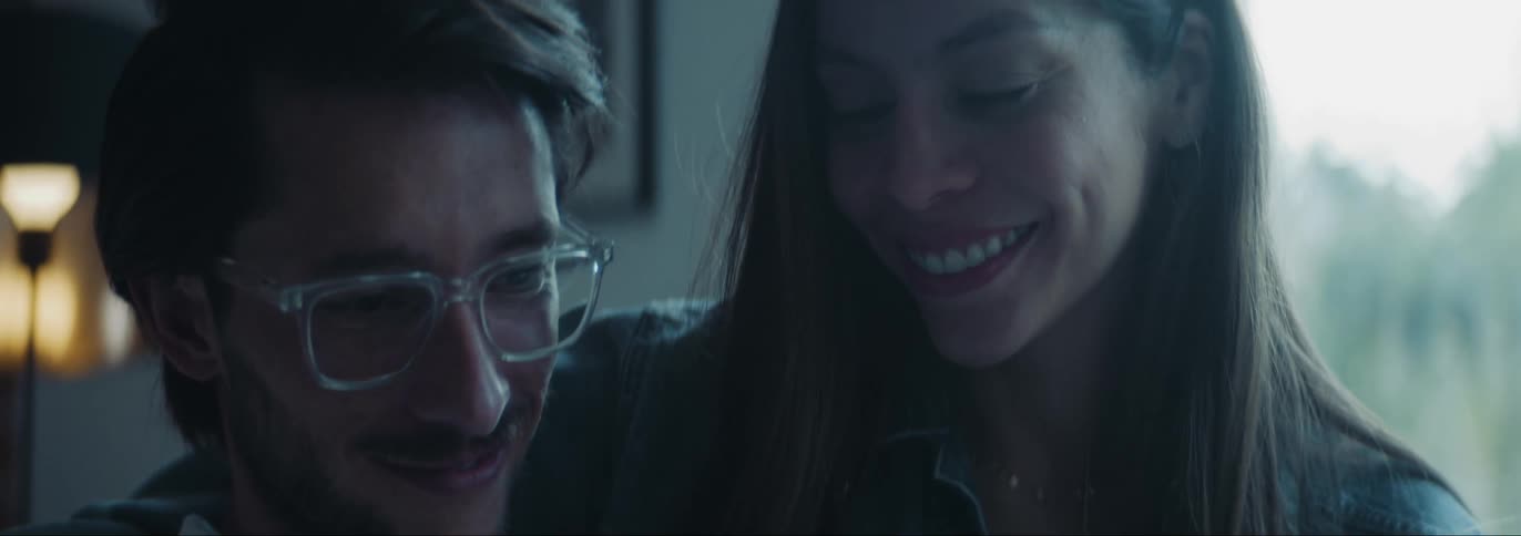 Woman hugging her husband and smiling inside the house in front of a glass window