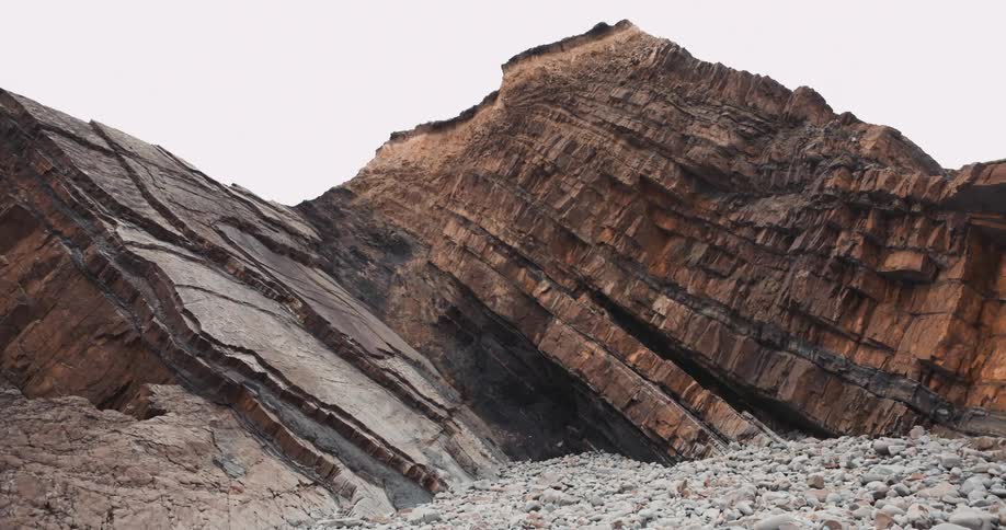 Layered rocks along a mountain ridge with stones on the ground