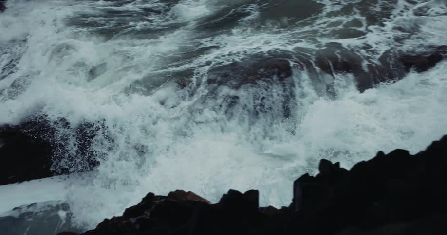 Ocean waves crash against oceanside cliff