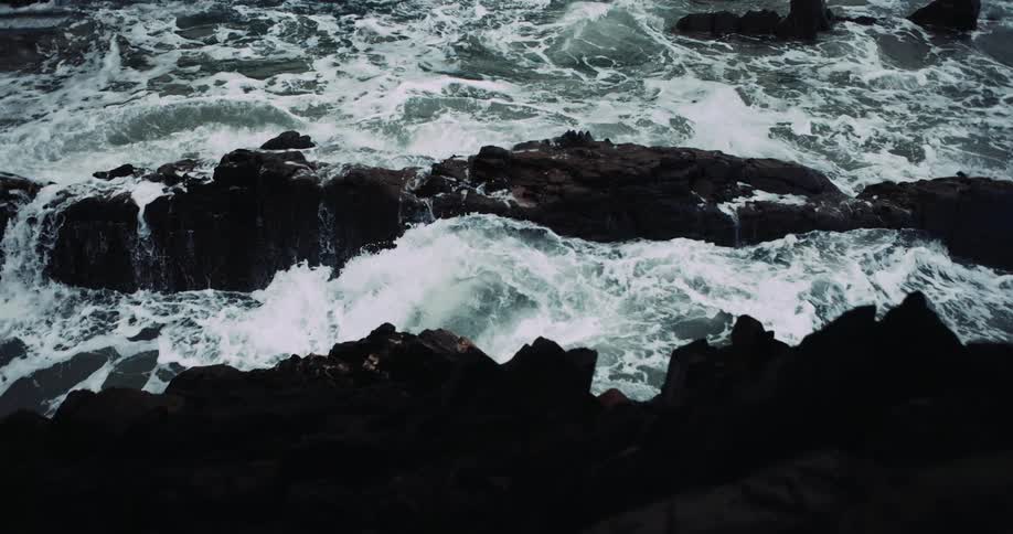 Foamy ocean waves crash against oceanside cliff