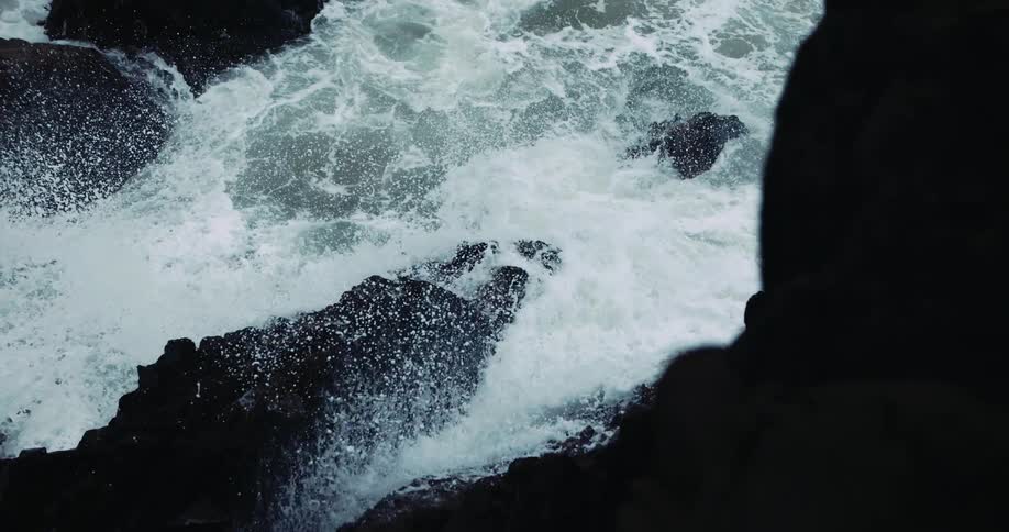 Ocean waves crash into the large rocks