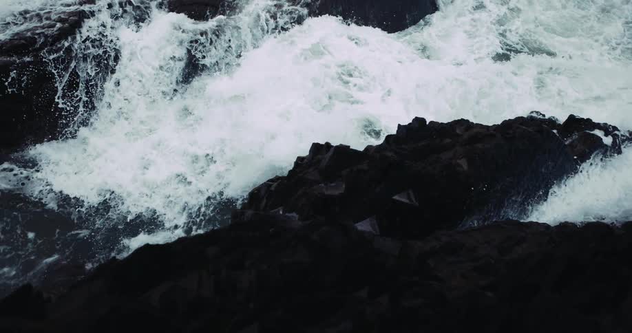 The waves crash against the rocks on the shore