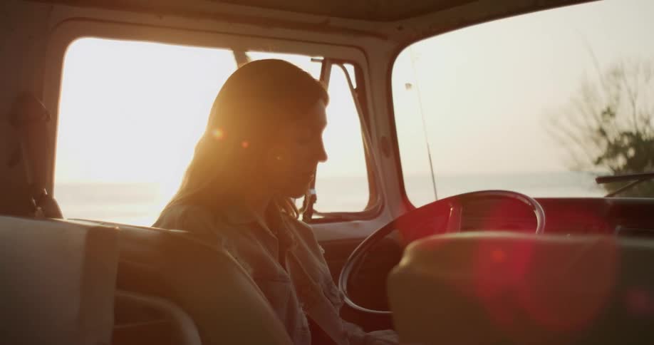 A woman sits in the van at sunrise