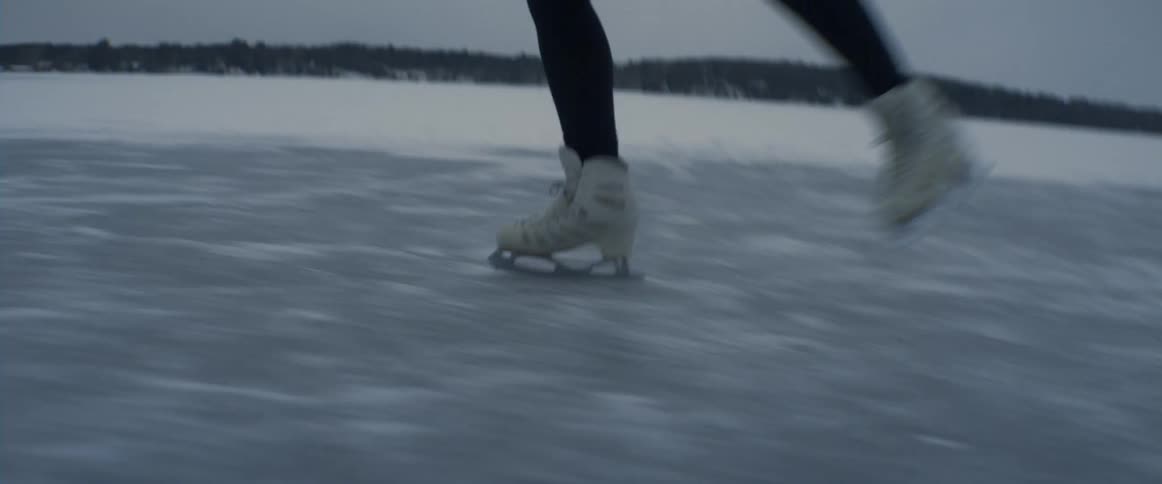 A woman is ice skating on the frozen lake