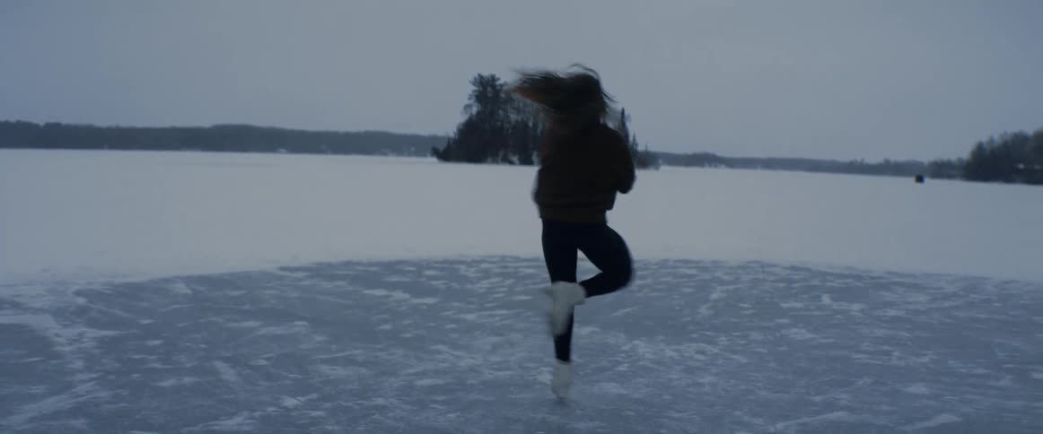 A woman figure skates on the iced over lake