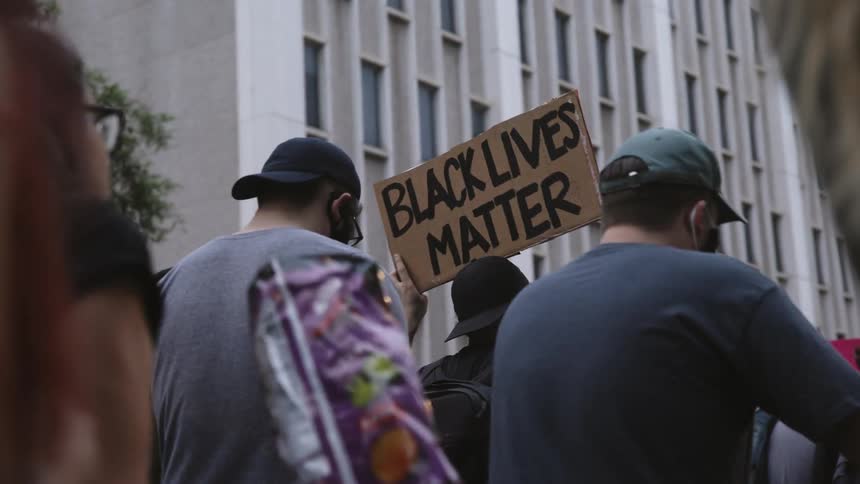 A crowd of people are protesting in a downtown city