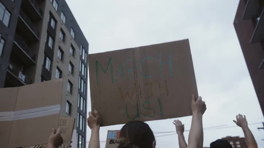 A group of people protests against racisim by carrying black lives matter signs