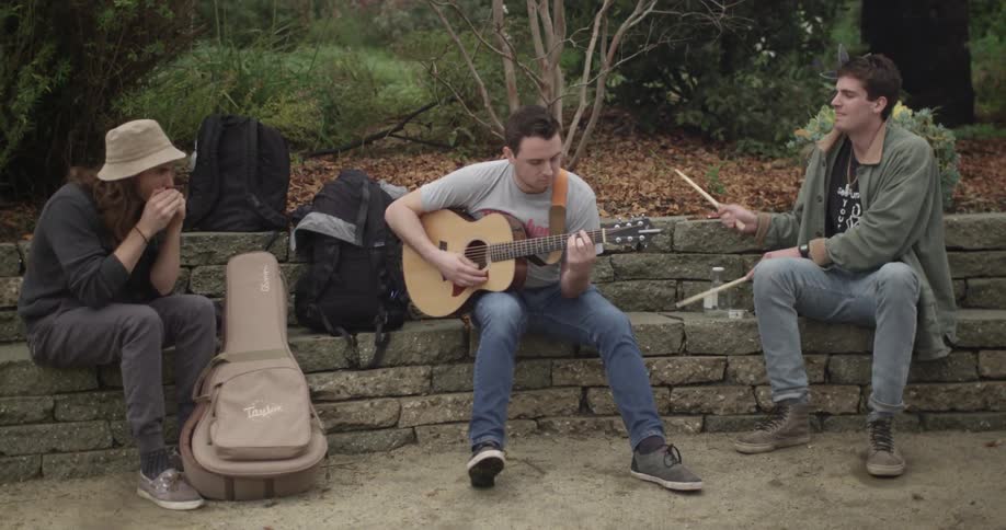 Three people play music outdoors