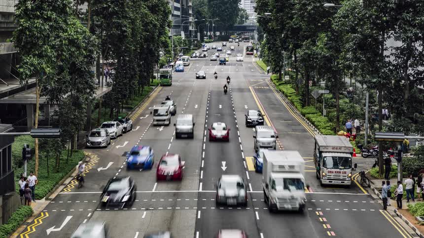 A crowd of pedestrians crosses a busy city street when traffic pauses