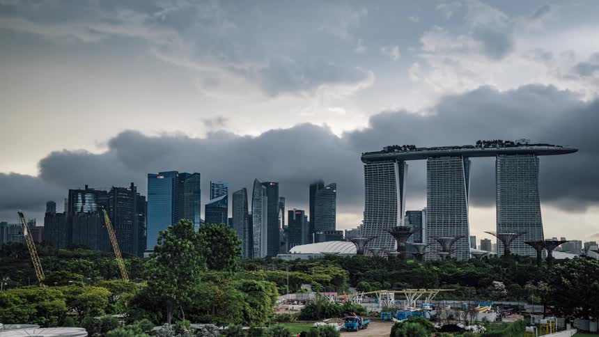 A time lapse of dark storm clouds moving over office buildings and constructions cranes as people walk to vehicles