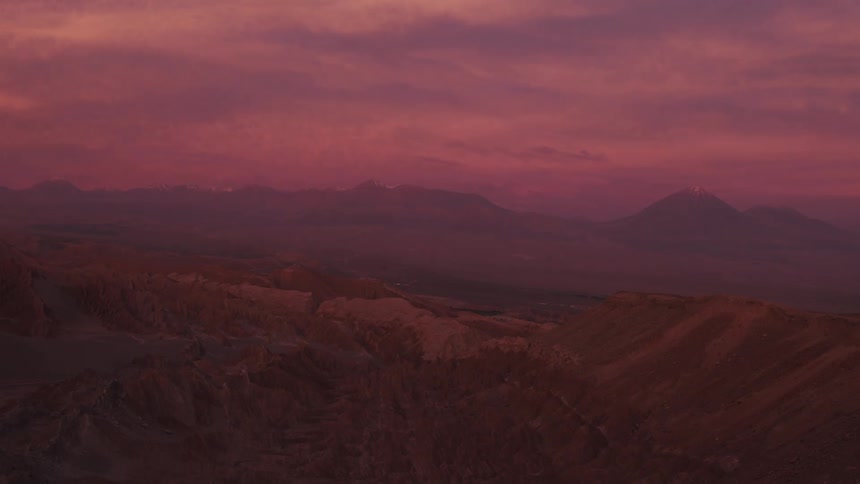 Aerial view of a red dark cloudy sunset over the hills and mountains