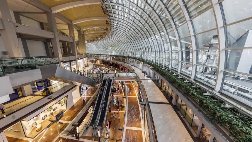 People walking around and riding the escalator at the shoppes at marina bay sands in singapore