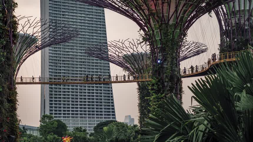 A time lapse of people walking across a bridge in front of an office building in a city