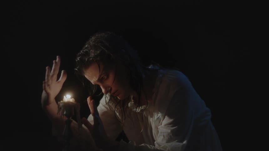 A woman is waving her hands around the candle