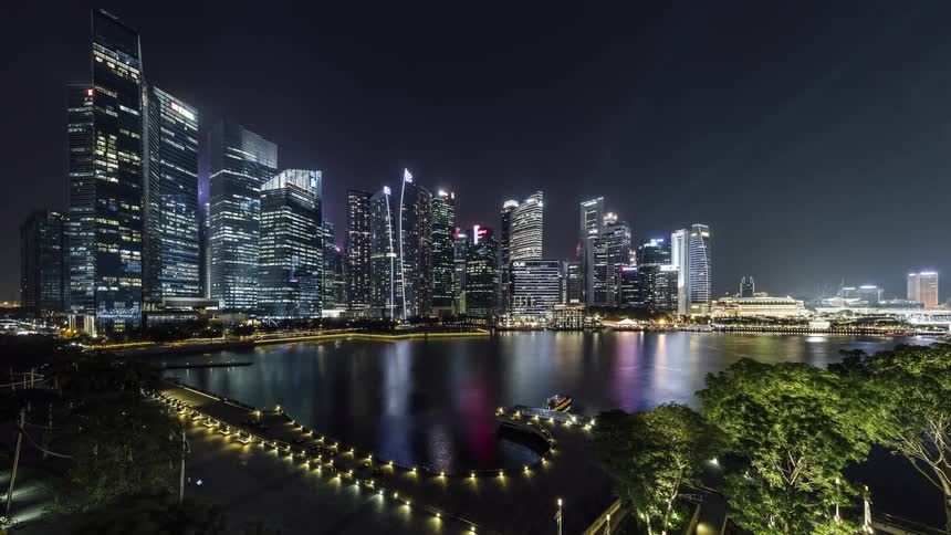Illuminated city skyscrapers high rise buildings and bridges next to sea at night