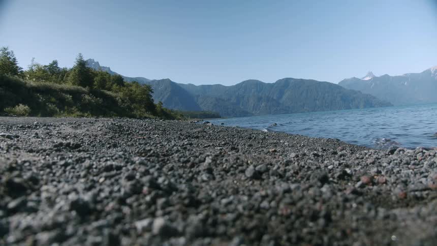 Waves rolling in to the shore with a mountains in the background