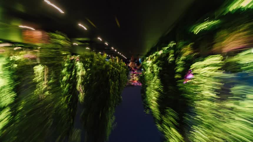 Twisting footage of pedestrians walking on a walkway through a park in singapore at night