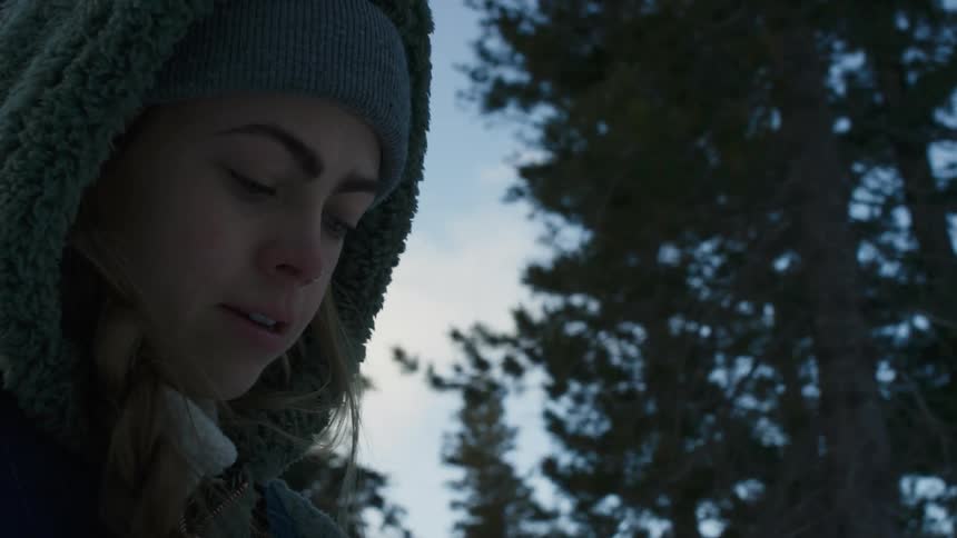 Close up of a young woman wearing thick winter clothes on a forest at evening