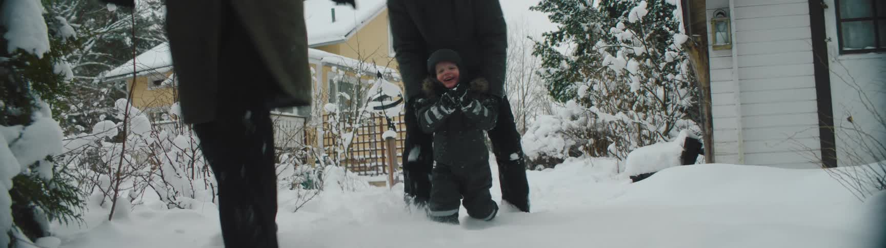 Mom leads the way through the snow as dad helps a rosy cheeked child
