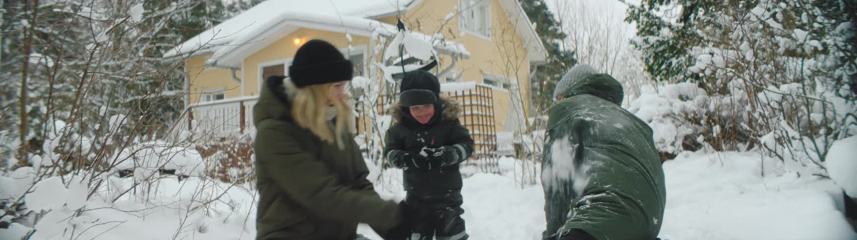 A family have a snowball fight in the yard