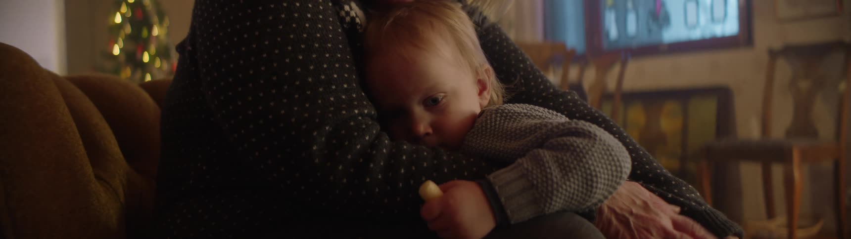 Father playing with his son on his arms in the living room near a christmas tree