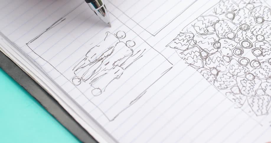A person is drawing with a pen in a notebook