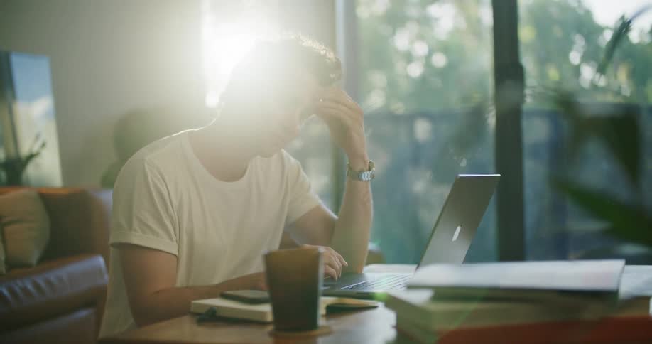 Young tired man working from home in the living room closes a laptop in the morning