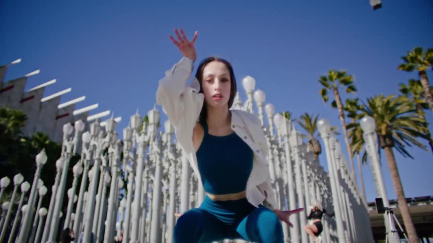 A woman dances in front of a public art display near a museum