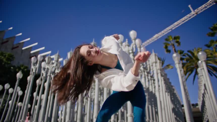 A woman is dancing near the rows of lamp posts