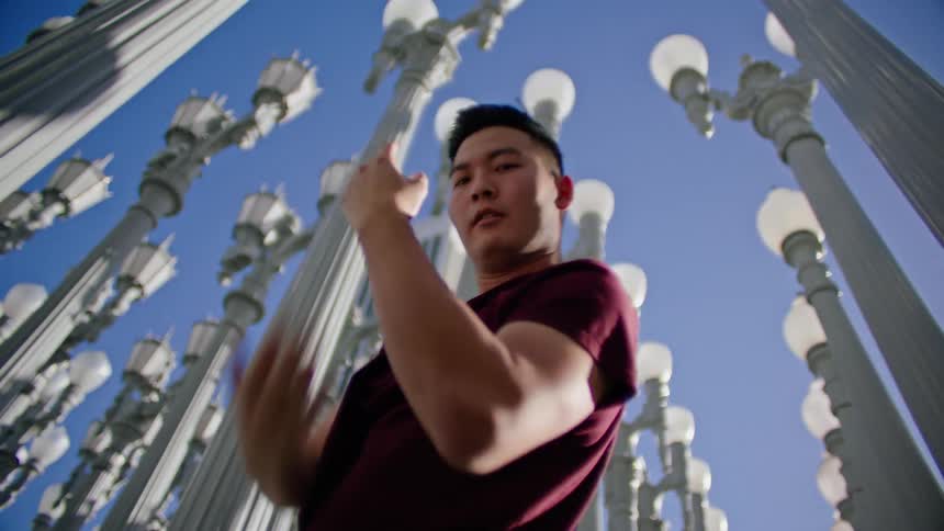 Male dancer dances near art display of rows of streetlamps