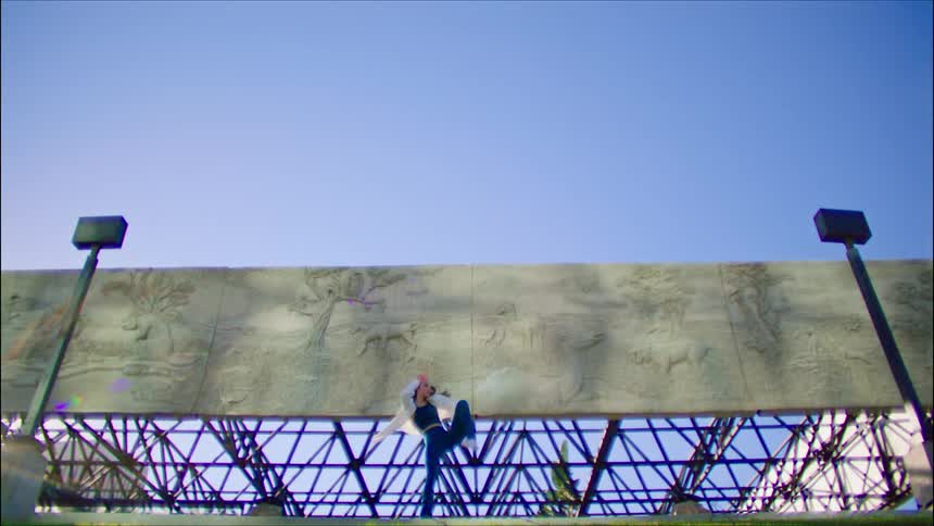 A woman is dancing right by the billboard