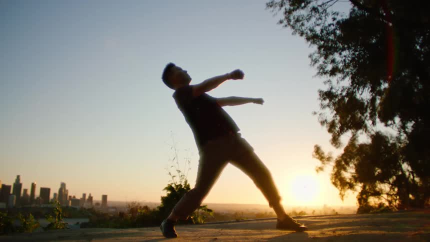 A man dances in a public park at a vantage point of downtown