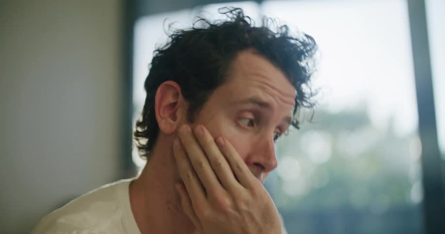 Bored man in white shirt sits at desk working