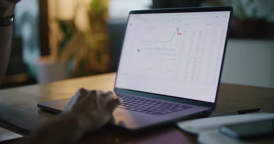 A man works on spreadsheets and graphs on his laptop