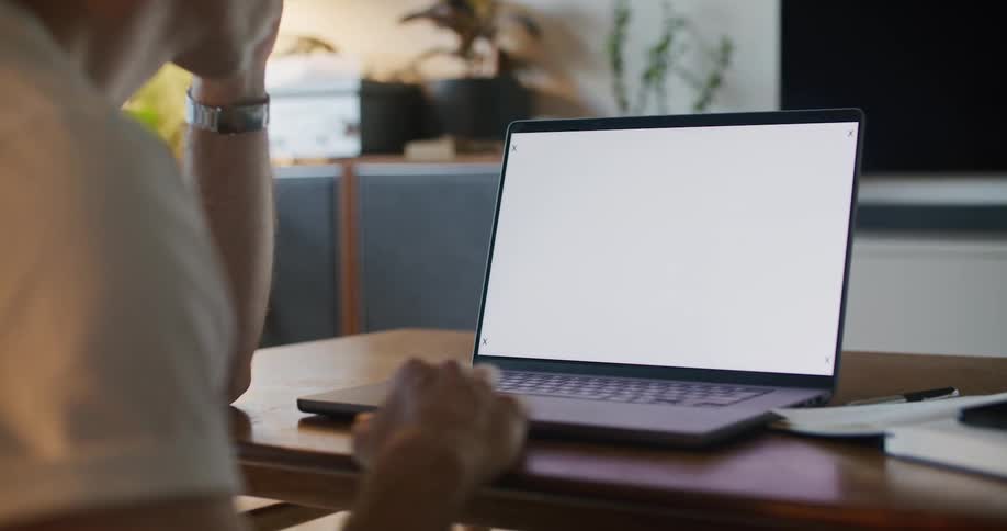A man sits at a laptop with motion tracking markers on the screen