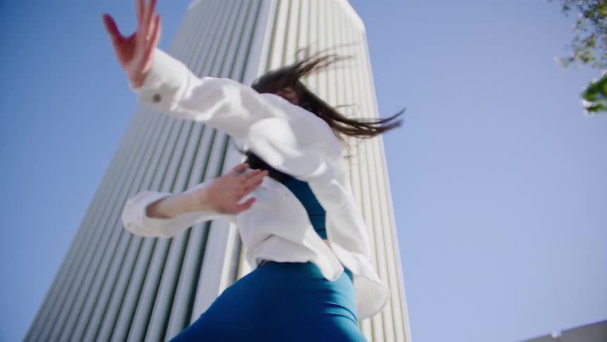 A woman dances and bends while the wind whips her long hair