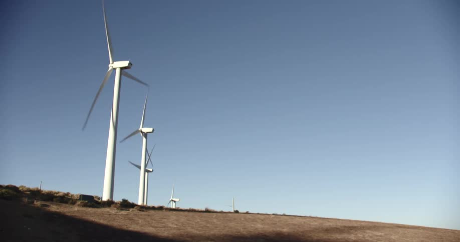 Wind turbines are spinning on a wind farm under a clear sky
