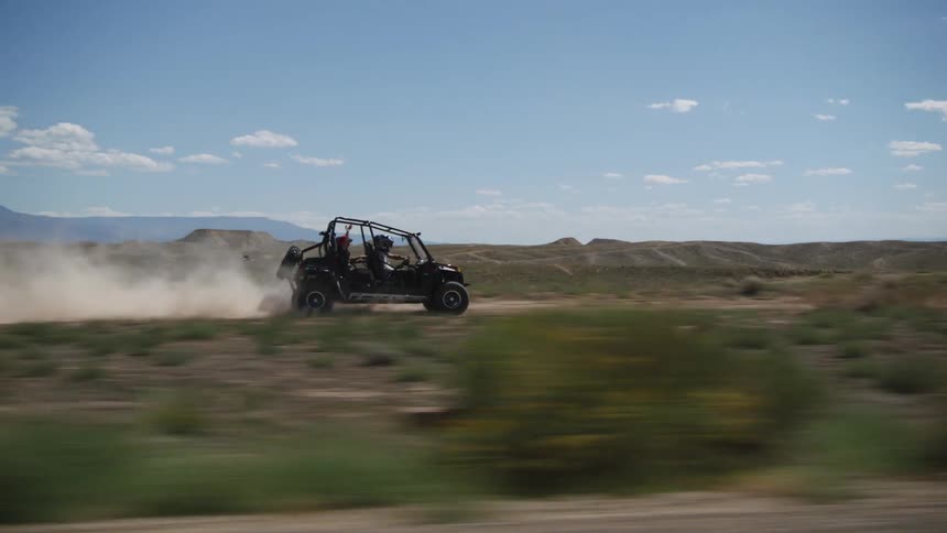 Atv off roading at high speed on in desert as drone flys overhead