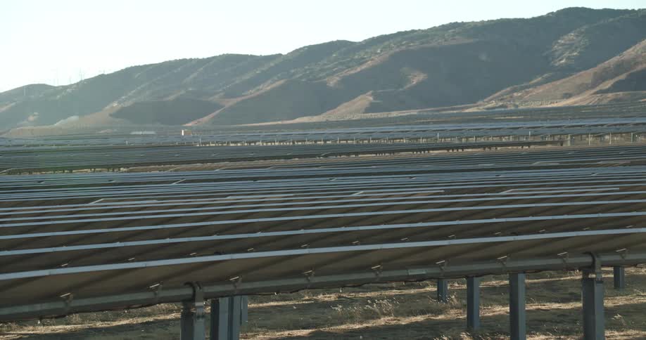 Solar panels on a solar farm and there are mountains in the distance