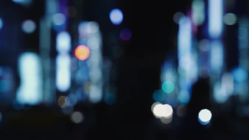 Out of focus shot of people walking downtown in the city at night