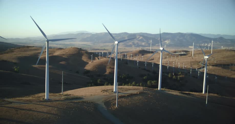 Aerial view of wind turbines running on wind farm in the hills