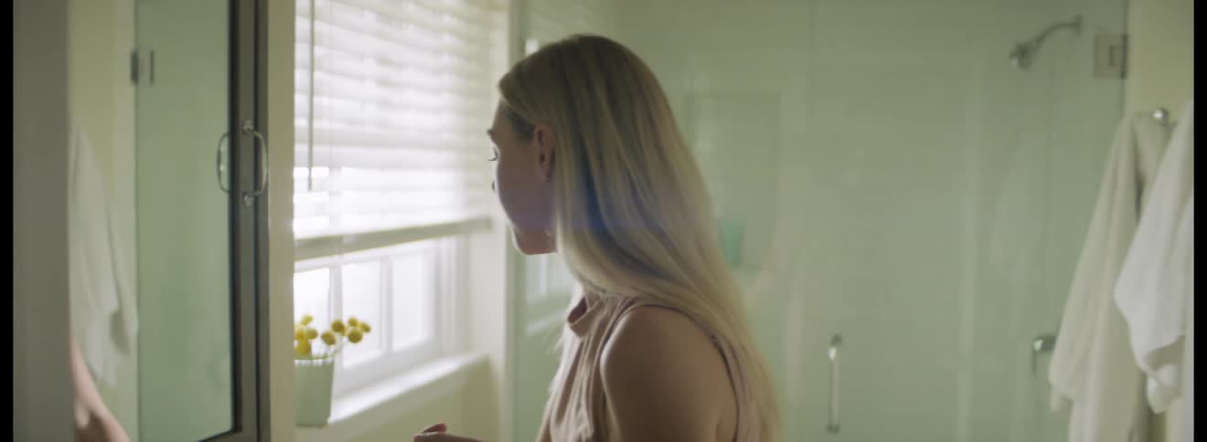 Blonde woman walks into bathroom and takes pills that came from a packet