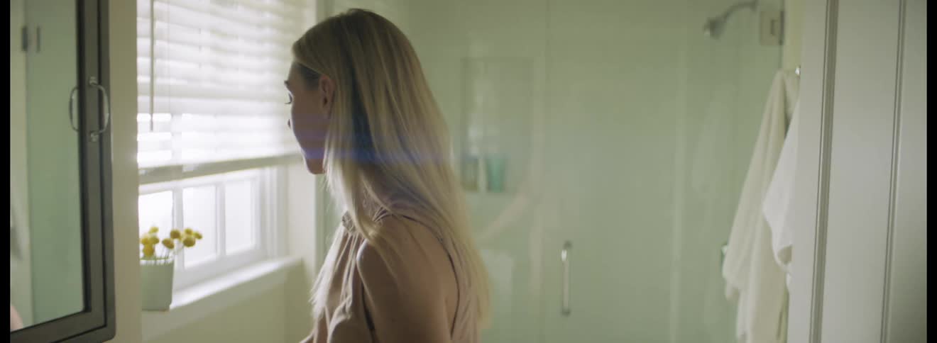 A woman takes a pill in the bathroom