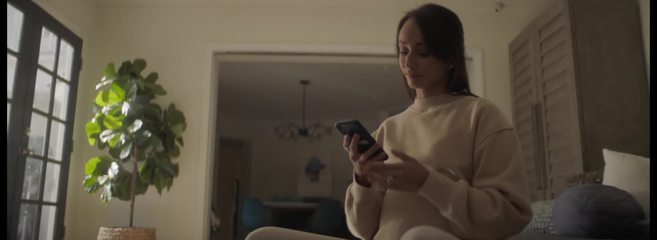 A woman is using her cell phone at home