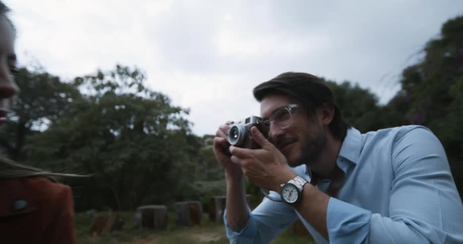 Man taking photo of female with vintage camera outdoors in nature